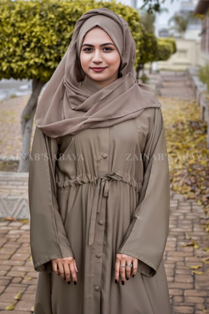 Front Open Abaya in Skin Color which is crafted in premium nida korean fabric featuring the button style on front stretchy elastic and plates style as well as a matching scarf in chiffon fabric.