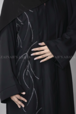 Black Colored Front Open Abaya for women in Nida Korean Fabric with Embroidery and Stone work on front as well as matching scarf in chiffon fabric.